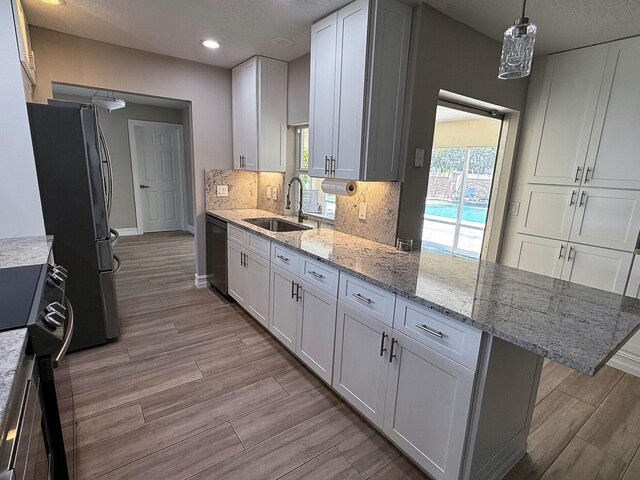 1807 Crafton Rd, North Palm Beach, FL 33408 - kitchen featuring a sink, white cabinets, light wood-style floors, a peninsula, and recessed lighting