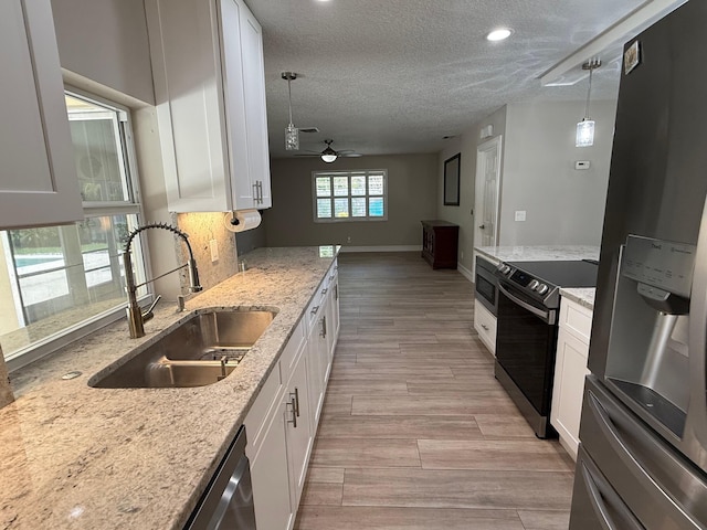 1807 Crafton Rd, North Palm Beach, FL 33408 - kitchen featuring stainless steel appliances, a sink, light wood-style flooring, a textured ceiling, and white cabinets