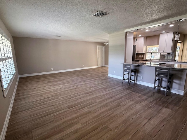 1807 Crafton Rd, North Palm Beach, FL 33408 - kitchen featuring dark wood-style flooring, white cabinetry, baseboards, a breakfast bar, and a textured ceiling