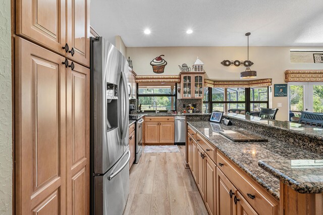 11700 Island Lakes Ln, Boca Raton, FL 33498 - kitchen featuring stainless steel appliances, light wood finished floors, glass insert cabinets, dark stone counters, and pendant lighting