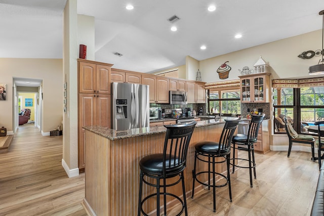 11700 Island Lakes Ln, Boca Raton, FL 33498 - kitchen with stainless steel appliances, vaulted ceiling, a kitchen island, tasteful backsplash, and light wood-type flooring
