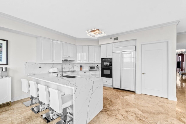 3740 S Ocean Blvd Unit 403, Highland Beach, FL 33487 - kitchen featuring ornamental molding, a peninsula, decorative backsplash, white cabinets, and light stone counters