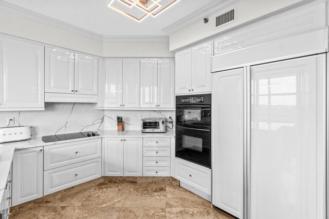 3740 S Ocean Blvd Unit 403, Highland Beach, FL 33487 - kitchen with black appliances, white cabinets, crown molding, under cabinet range hood, and tasteful backsplash