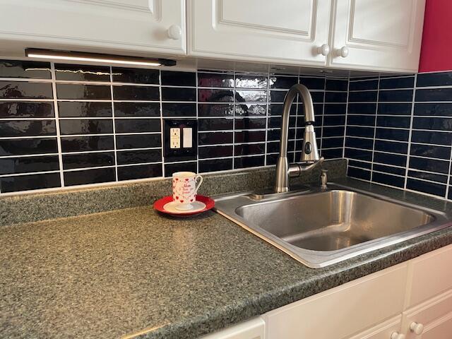 111 SE 1st St Unit 7, Boynton Beach, FL 33435 - kitchen view of a sink, white cabinets, decorative backsplash, and dark countertops