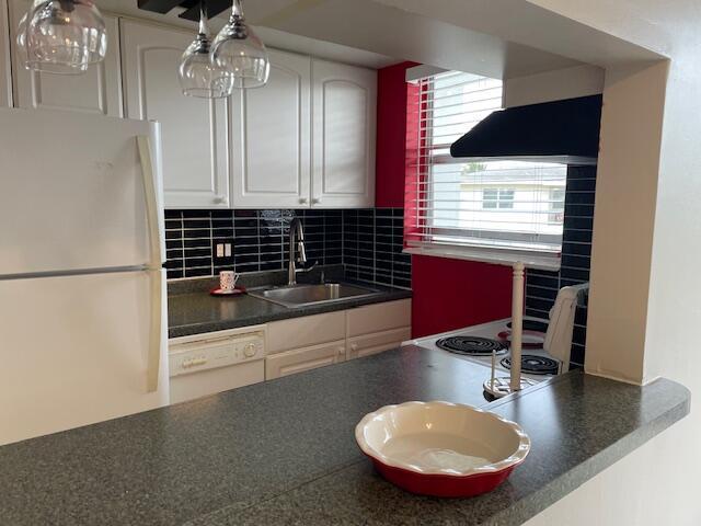 111 SE 1st St Unit 7, Boynton Beach, FL 33435 - kitchen featuring white appliances, a sink, dark countertops, under cabinet range hood, and white cabinets