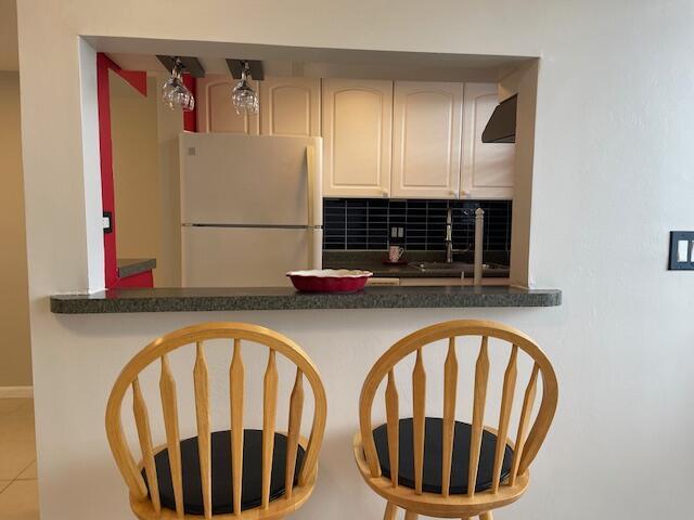 111 SE 1st St Unit 7, Boynton Beach, FL 33435 - kitchen with freestanding refrigerator, a sink, backsplash, and dark countertops