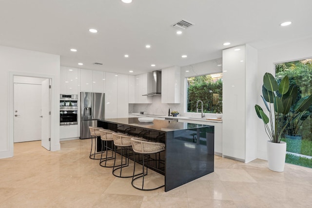 2646 NW 49th St, Boca Raton, FL 33434 - kitchen with modern cabinets, appliances with stainless steel finishes, wall chimney exhaust hood, a kitchen bar, and white cabinets
