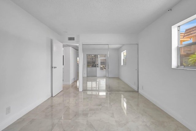 spare room with light marble finish flooring, a textured ceiling, and baseboards