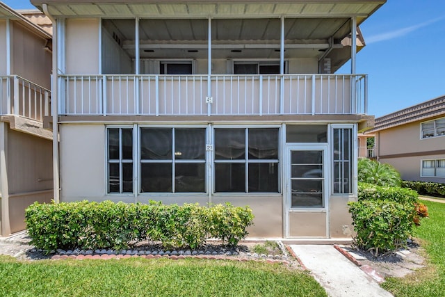 rear view of house featuring a balcony and stucco siding