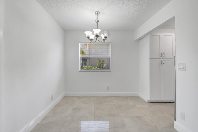 unfurnished dining area featuring a chandelier, a textured ceiling, baseboards, and light tile patterned floors