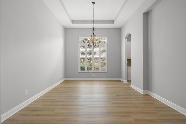 17009 SW Sapri Way, Port Saint Lucie, FL 34986 - unfurnished dining area with a raised ceiling, arched walkways, light wood-style floors, and a chandelier