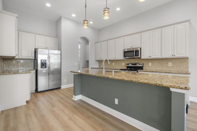 17009 SW Sapri Way, Port Saint Lucie, FL 34986 - kitchen with appliances with stainless steel finishes, a sink, arched walkways, white cabinets, and tasteful backsplash
