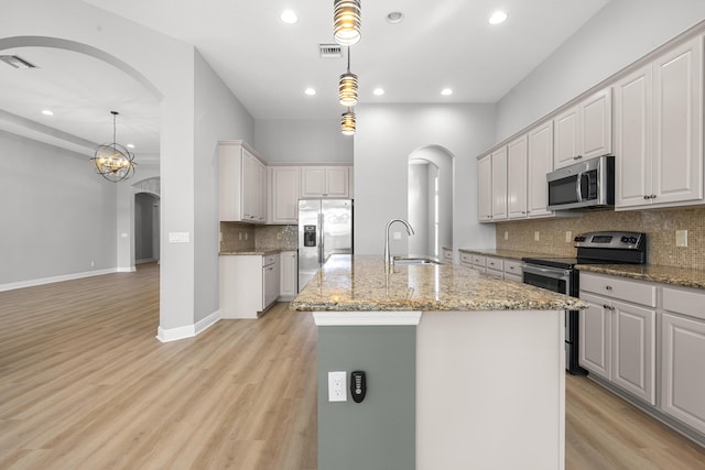 17009 SW Sapri Way, Port Saint Lucie, FL 34986 - kitchen with stainless steel appliances, a sink, arched walkways, light wood-style flooring, and recessed lighting
