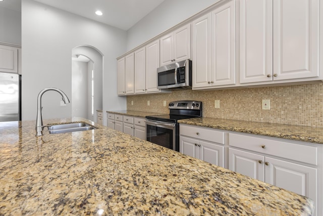 17009 SW Sapri Way, Port Saint Lucie, FL 34986 - kitchen featuring stainless steel appliances, a sink, arched walkways, white cabinetry, and tasteful backsplash