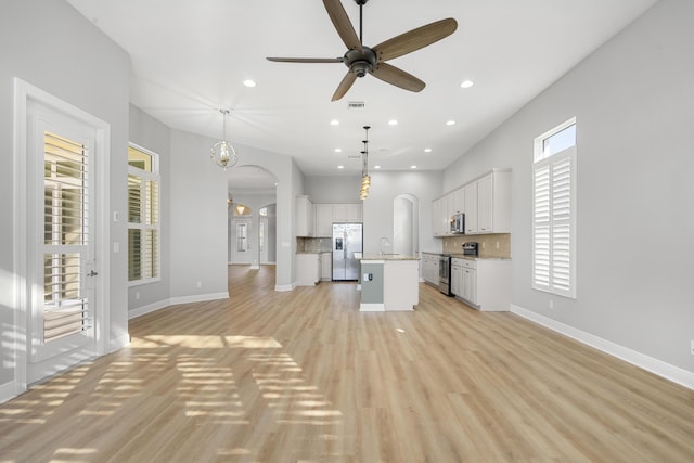 17009 SW Sapri Way, Port Saint Lucie, FL 34986 - unfurnished living room featuring arched walkways, a sink, ceiling fan, light wood-style floors, and baseboards