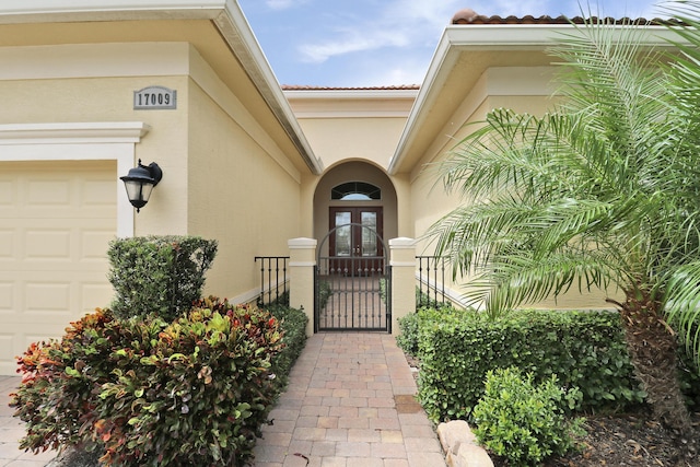 17009 SW Sapri Way, Port Saint Lucie, FL 34986 - entrance to property with french doors, stucco siding, a gate, an attached garage, and a tiled roof