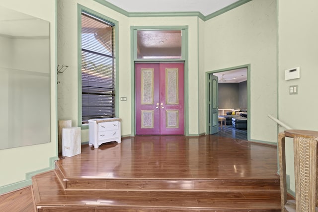 foyer entrance with hardwood / wood-style floors, french doors, ornamental molding, and baseboards