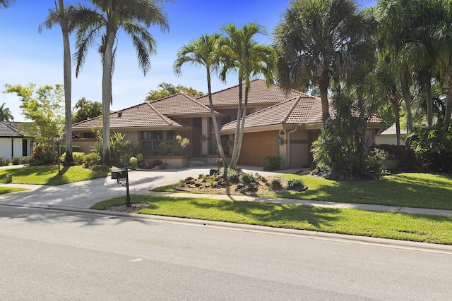 mediterranean / spanish-style house with concrete driveway, a tile roof, an attached garage, and stucco siding