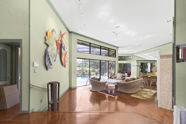 living area with wood finished floors and ornamental molding