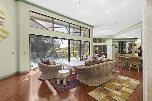 living area featuring a sunroom, wood finished floors, and baseboards