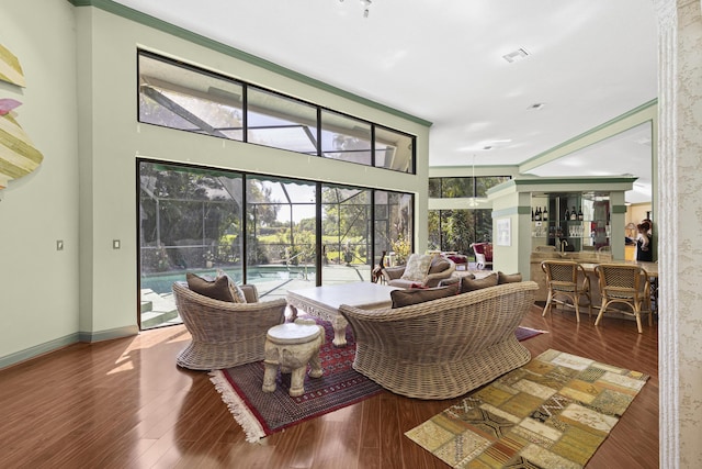living room featuring a sunroom, wood finished floors, crown molding, and baseboards