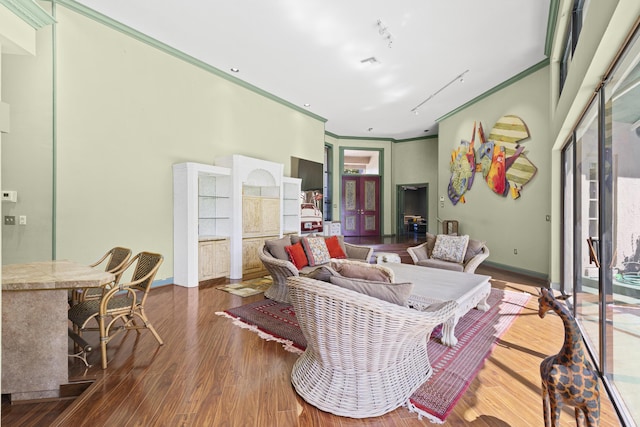 living room with wood finished floors, baseboards, and ornamental molding