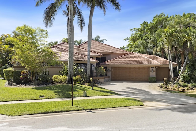 mediterranean / spanish-style house featuring a tile roof, a garage, stucco siding, a front yard, and concrete driveway