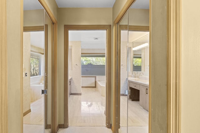 hall with a sink and light tile patterned floors