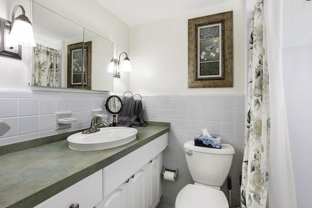 4001 S Ocean Blvd Unit 118, South Palm Beach, FL 33480 - full bathroom with tile walls, toilet, vanity, and a wainscoted wall