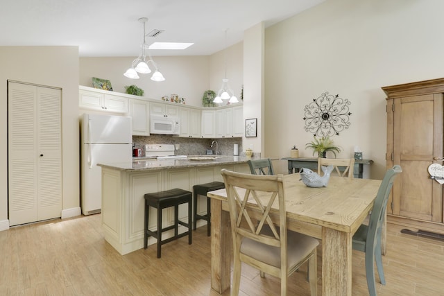 1801 S US Highway 1 Unit 7C, Jupiter, FL 33477 - dining space with high vaulted ceiling, a skylight, and light wood finished floors