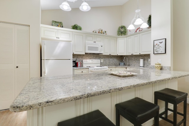 1801 S US Highway 1 Unit 7C, Jupiter, FL 33477 - kitchen with white appliances, a peninsula, light stone countertops, light wood-style floors, and backsplash
