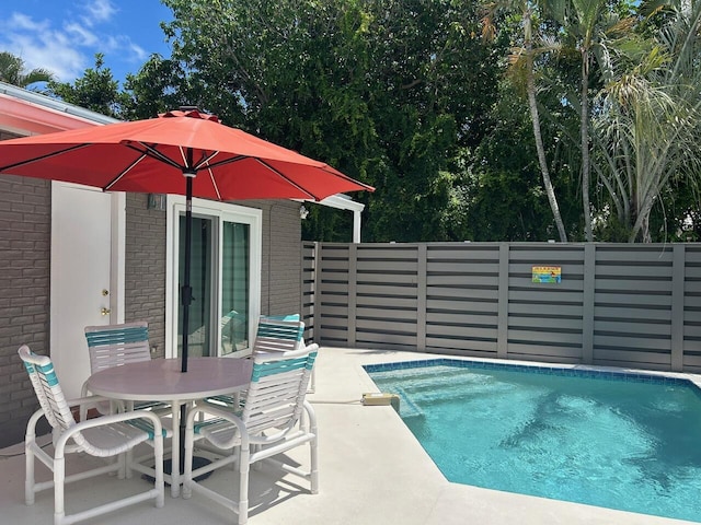 view of swimming pool with fence, outdoor dining space, and a patio