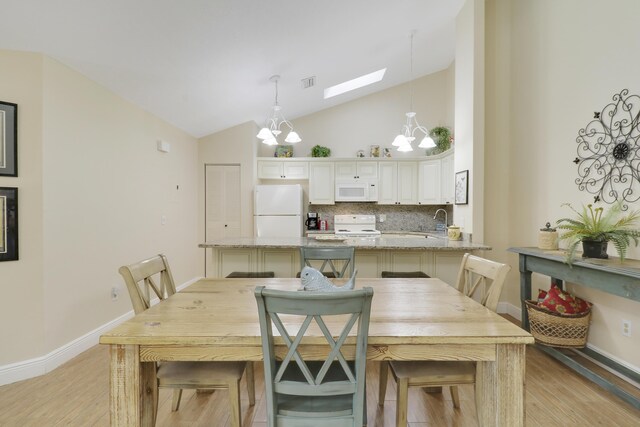 1801 S US Highway 1 Unit 7C, Jupiter, FL 33477 - dining room with a skylight, light wood-style flooring, a chandelier, baseboards, and high vaulted ceiling