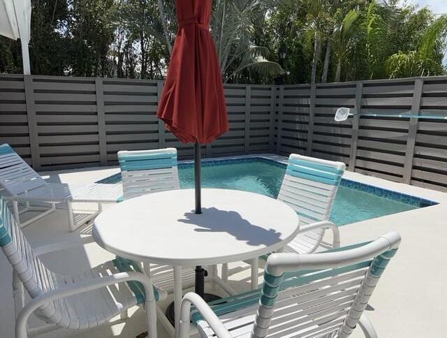 view of swimming pool featuring outdoor dining space and fence