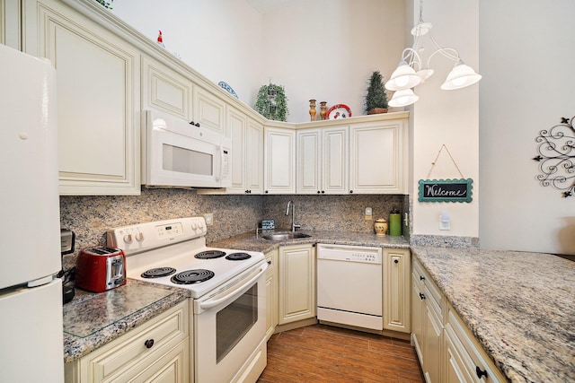 kitchen with white appliances, cream cabinetry, a sink, decorative backsplash, and wood finished floors