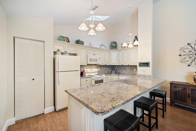 kitchen featuring white appliances, a peninsula, cream cabinets, light wood-style flooring, and high vaulted ceiling