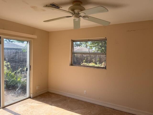 tiled empty room featuring baseboards and ceiling fan