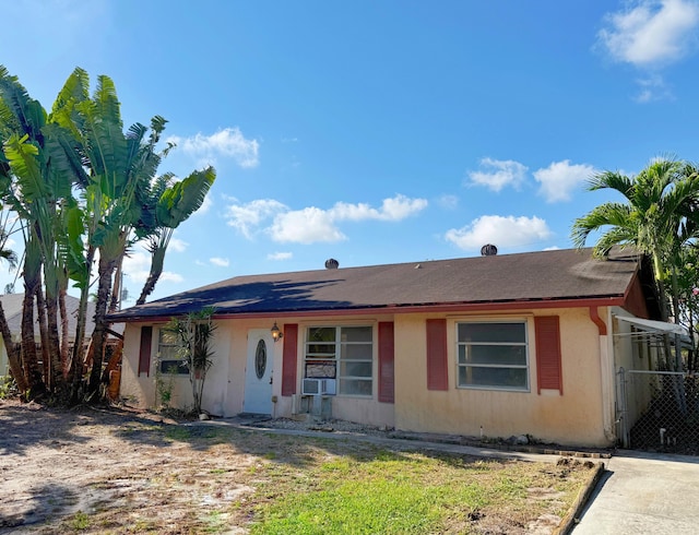 ranch-style home with stucco siding, cooling unit, and fence