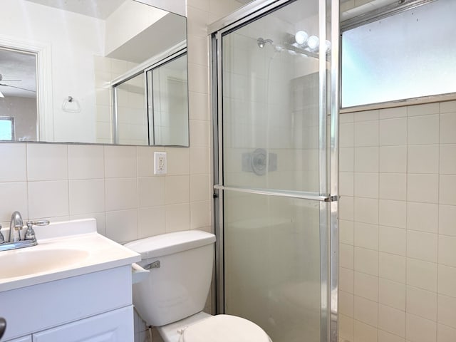 bathroom with tile walls, a shower stall, vanity, toilet, and backsplash