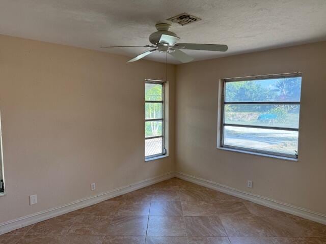 tiled spare room with ceiling fan and baseboards