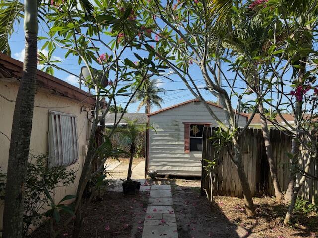 view of side of home featuring fence and an outbuilding
