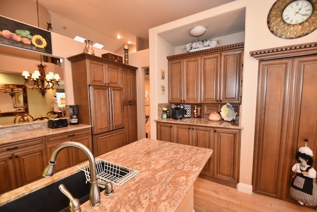 5845 NW 24th Ave Unit 1103, Boca Raton, FL 33496 - kitchen with brown cabinetry, light wood-type flooring, a sink, and light stone countertops
