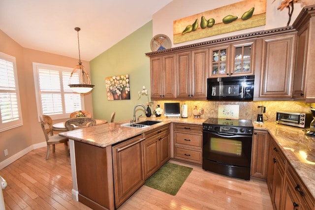 5845 NW 24th Ave Unit 1103, Boca Raton, FL 33496 - kitchen featuring black appliances, a sink, vaulted ceiling, a peninsula, and decorative backsplash