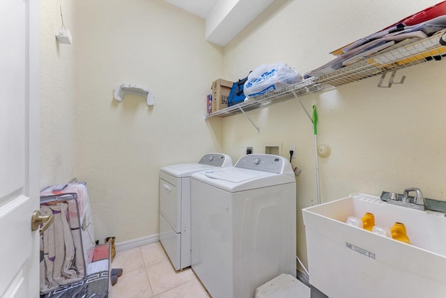 washroom featuring washer and clothes dryer, light tile patterned floors, and baseboards