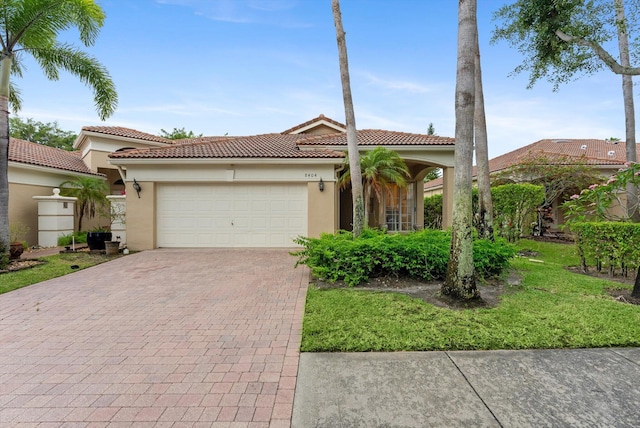 mediterranean / spanish-style house featuring decorative driveway, a garage, a tiled roof, and stucco siding