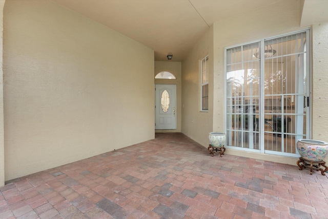 view of exterior entry with stucco siding and a patio area