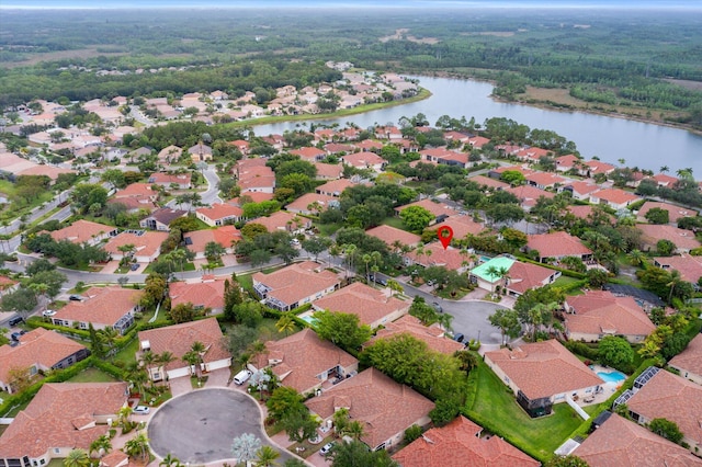 view of property location featuring a large body of water, nearby suburban area, and a heavily wooded area
