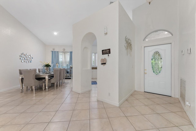 entrance foyer with arched walkways, light tile patterned floors, and baseboards