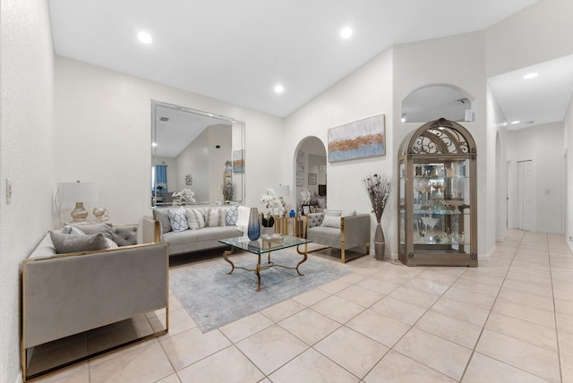 living room with arched walkways, vaulted ceiling, light tile patterned floors, and recessed lighting