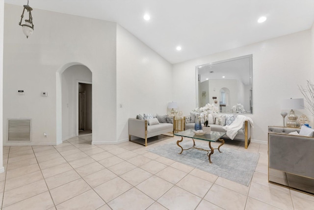 living area with arched walkways, light tile patterned floors, recessed lighting, baseboards, and a towering ceiling